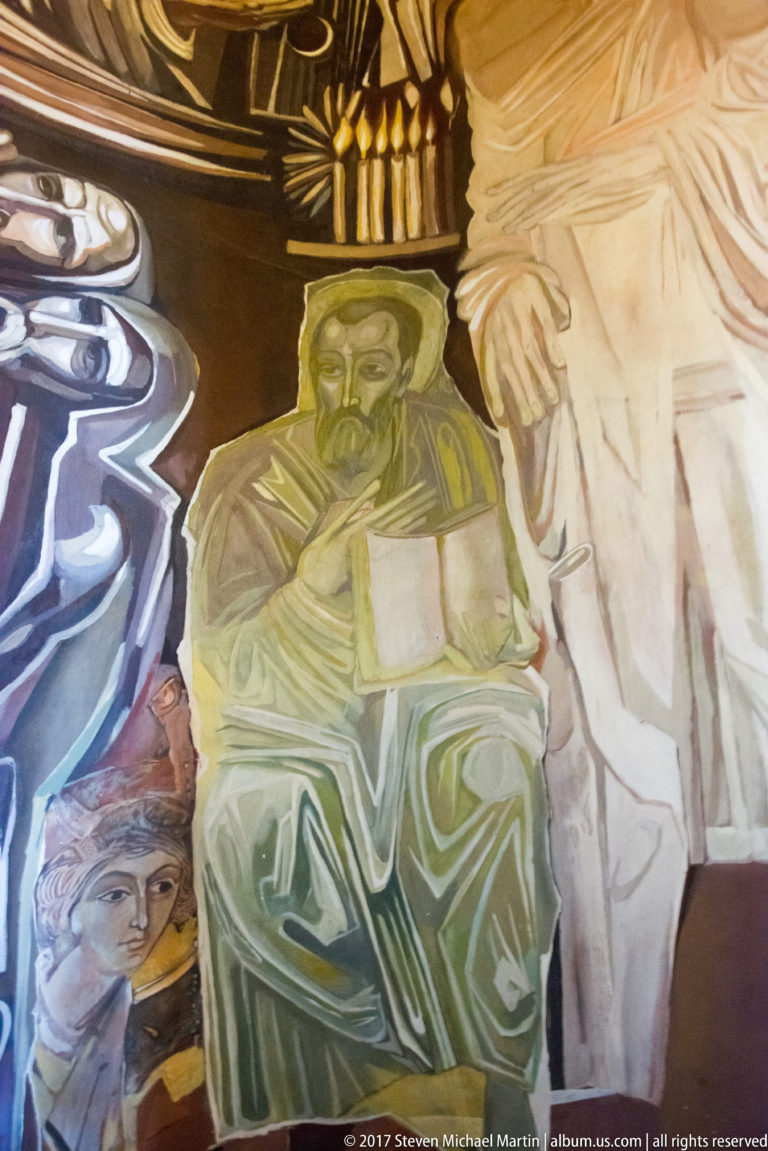 Teofan Sokerov mural of a green-robed bearded seated figure holding a pale rectangular object, with candles behind.