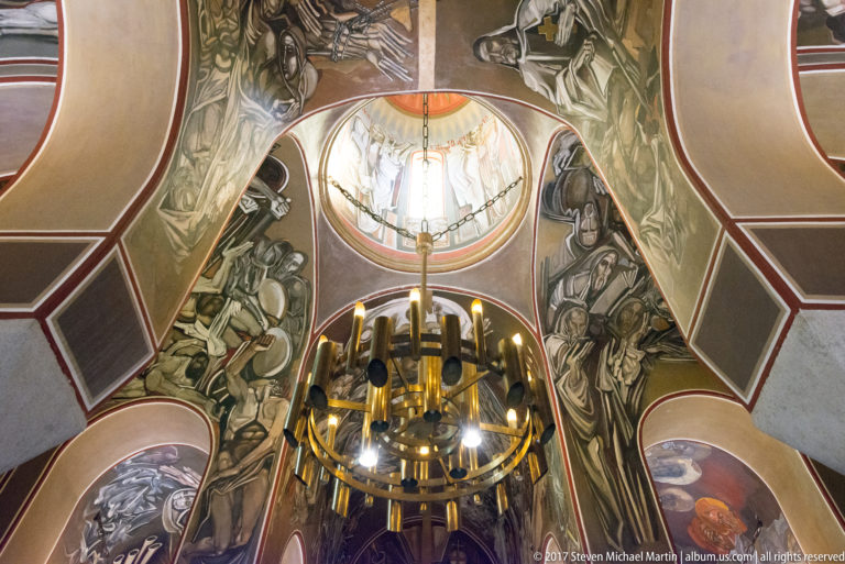 Upward view of the Patriarchal Church with circular chandelier, bright dome, and monumental murals by Teofan Sokerov.