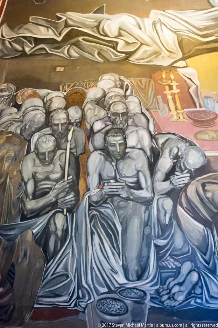 Teofan Sokerov mural crowded with seated and standing gray-toned figures, with candles and warm details at upper right.