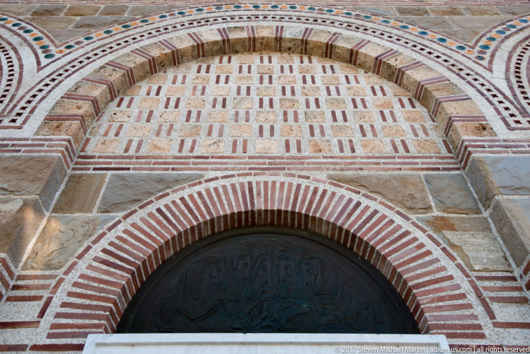 Arched doorway of the reconstructed Patriarchal Church framed by concentric red-brick and pale-stone decorative masonry.