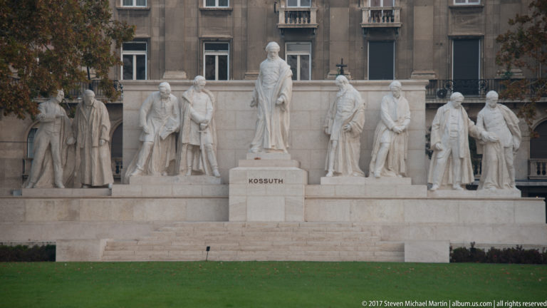 Front view of the Kossuth Memorial, with Lajos Kossuth centered above flanking stone figures and the name KOSSUTH on the pedestal.