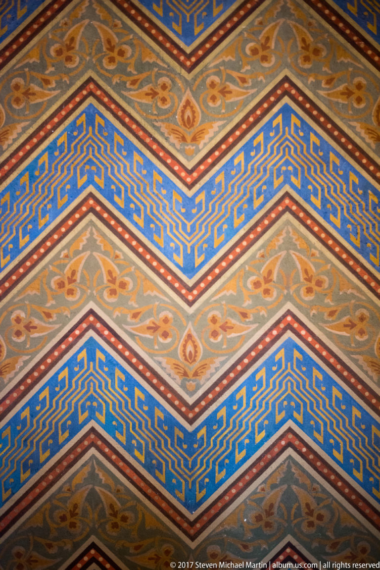 Close detail of blue, gold, and cream chevron bands with scrolling painted ornament inside Matthias Church.