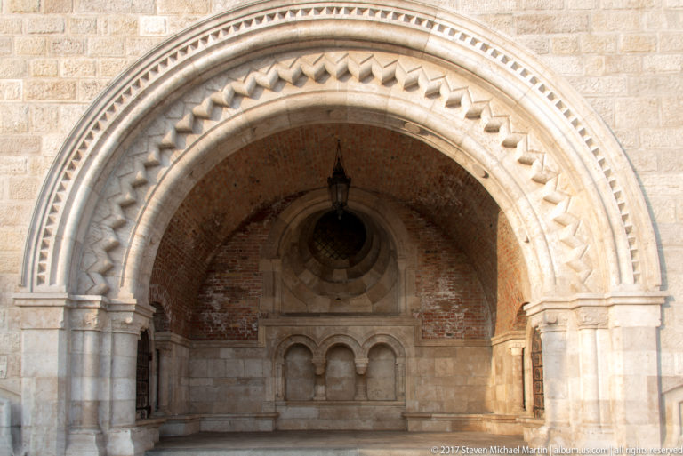 Deep round-arched stone alcove at Fisherman’s Bastion with zigzag carving, brick vaulting, and a small triple-arched feature.