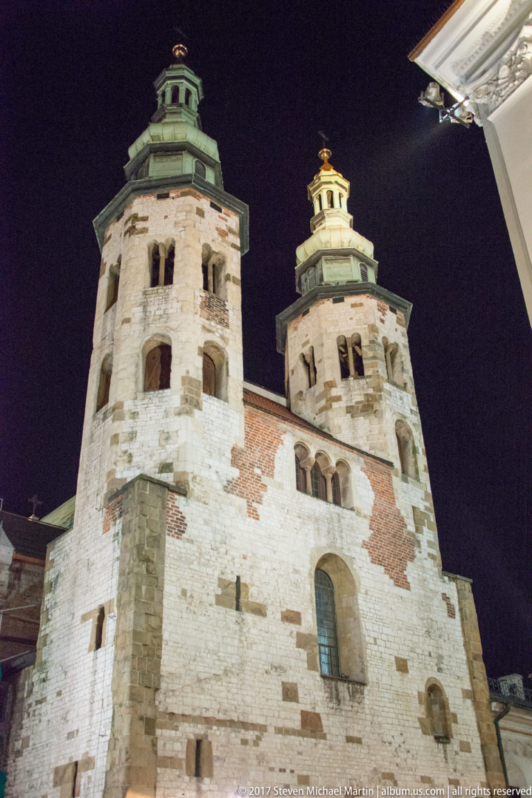 Low-angle night view of the Romanesque Church of St. Andrew in Krakow, showing its massive twin towers and baroque cupolas.