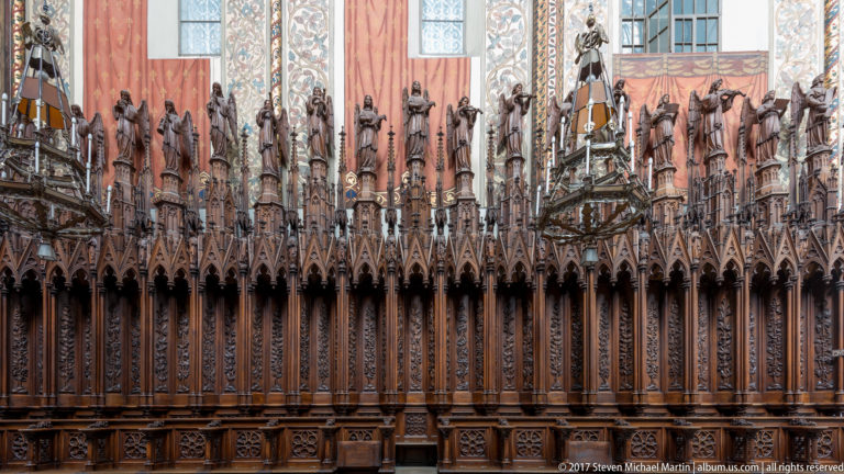 Elaborately carved Gothic choir stalls in Kraków with pinnacles, canopies, and rows of standing saint figures.