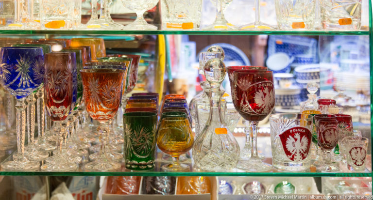 Colorful souvenir glasses in Kraków, including red vessels marked POLSKA and decorated with the white Polish eagle.