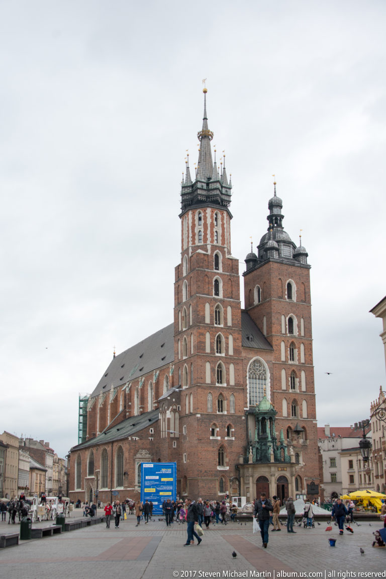 St. Mary’s Basilica on Kraków’s Main Market Square, with unequal brick towers, Gothic façade, and large traceried window.