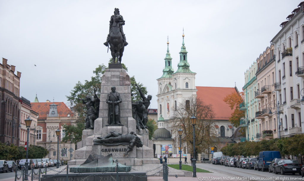 Grunwald Monument on Matejko Square in Kraków, with equestrian figure above sculptural groups and St. Florian’s Church behind.