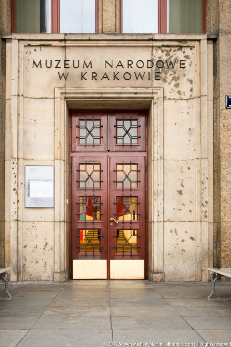 Main entrance of the National Museum in Kraków with Polish inscription above geometric gridded double doors.