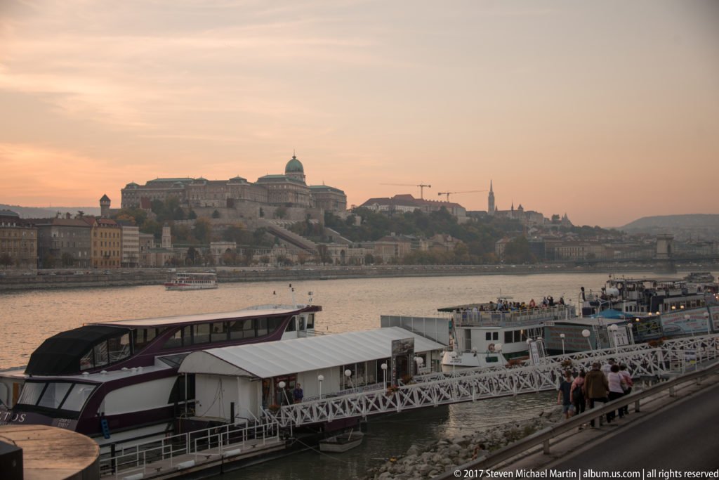 Buda Castle and Royal Palace on Castle Hill across the Danube, with riverboats and docks in the foreground.