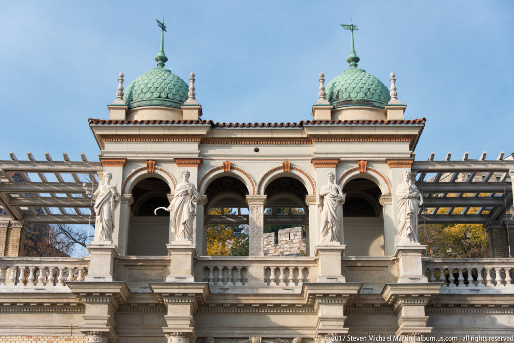 Symmetrical arcade with sculpted figures and two green-tiled domes at the Castle Garden Bazaar.