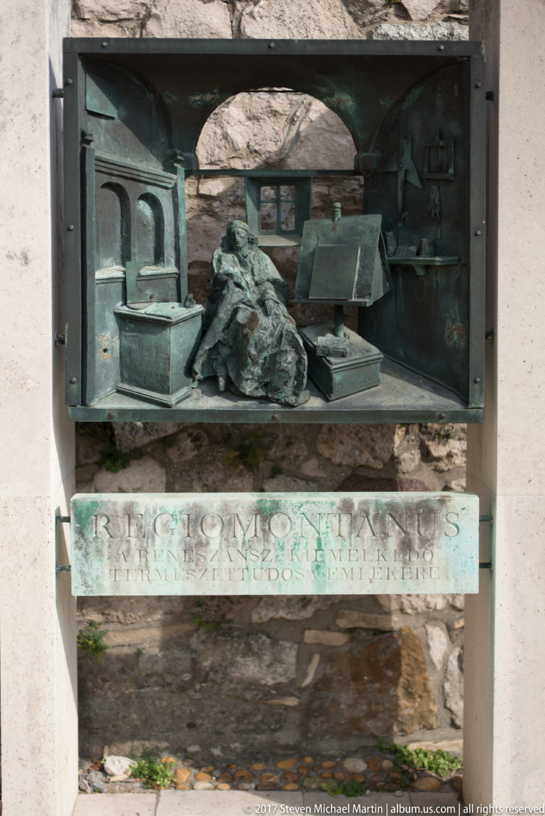 Bronze relief plaque with an inscribed panel mounted in a stone wall on Castle Hill.
