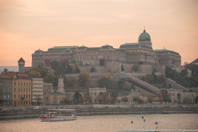 Royal Palace of Buda Castle above the Danube, with its central dome and a sightseeing boat below.