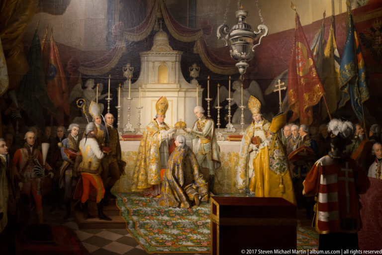 Historical court ceremony before an altar, with clergy, banners, attendants, and a kneeling central figure.