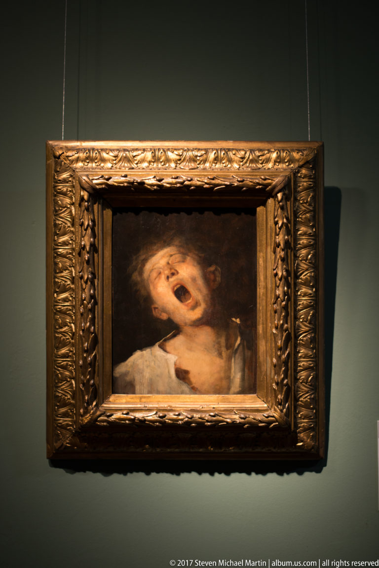 Small framed painting of an expressive upturned face with open mouth against a dark background.