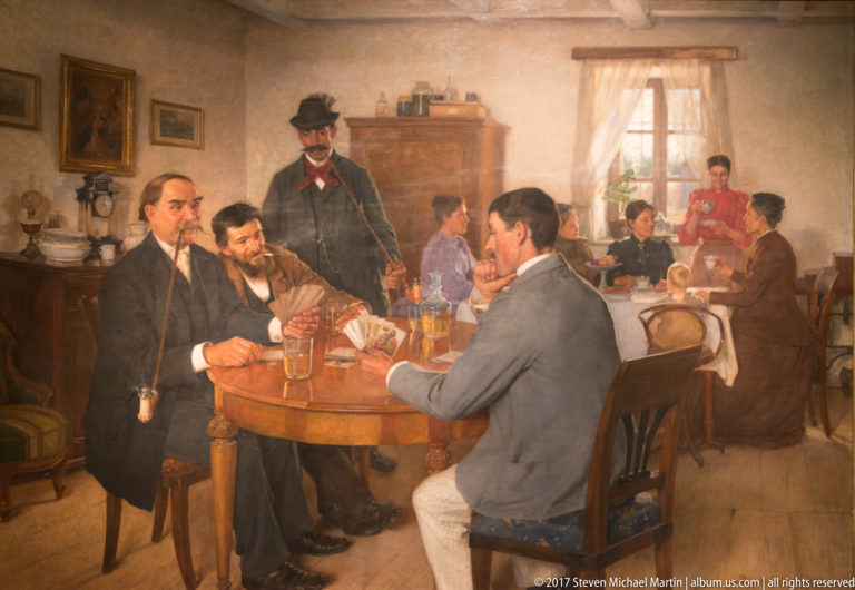 Genre painting of men drinking around a round table in a busy tavern or café interior.
