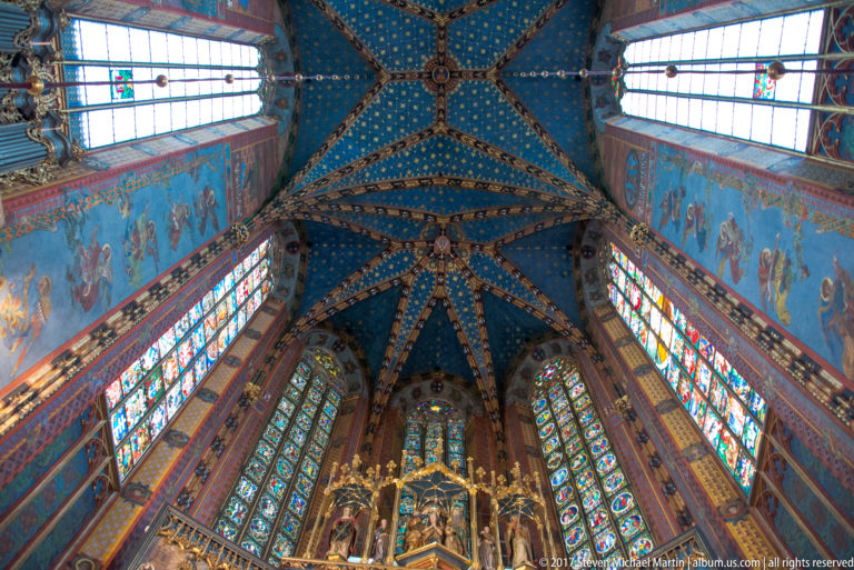 Upward chancel view from the top of the Veit Stoss Altarpiece to blue starry vaulting and tall stained-glass windows.