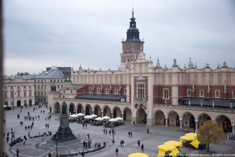 Elevated view of Town Hall Tower above the Cloth Hall and Main Market Square, with surrounding historic buildings and pedestrians.