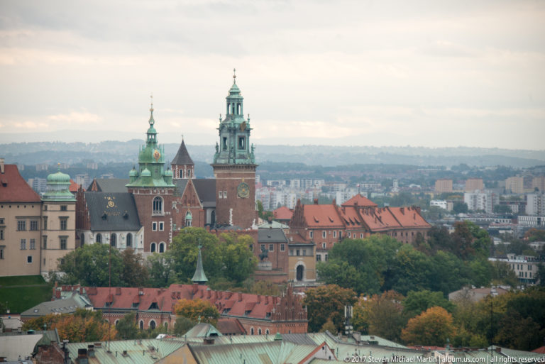 Closer elevated view of Wawel Hill with cathedral towers, green-patinated roofs, red masonry, and adjoining Royal Castle buildings.
