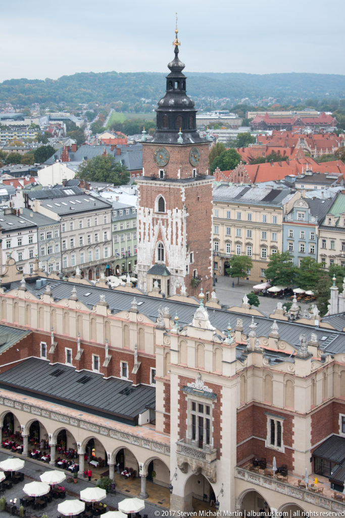 Elevated view of Town Hall Tower behind the arcaded Cloth Hall, with historic townhouses surrounding Krakow’s Main Market Square.