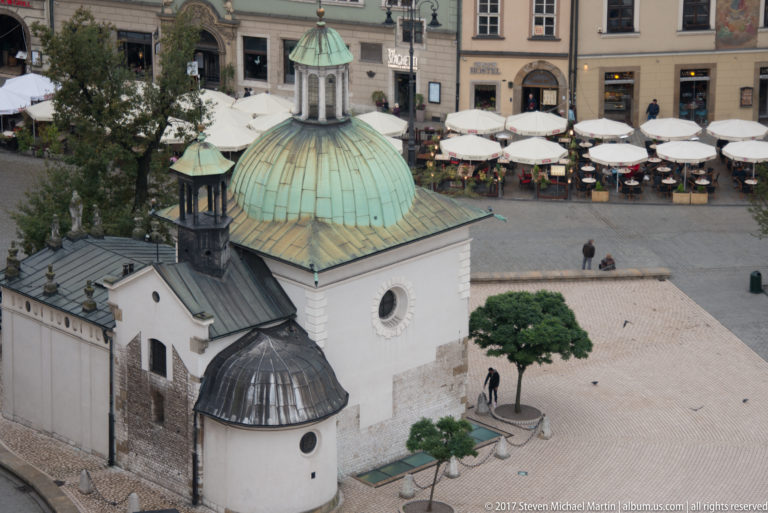 Closer elevated view of St. Adalbert Church showing its large green copper dome, small lantern, rounded annex, and white walls.