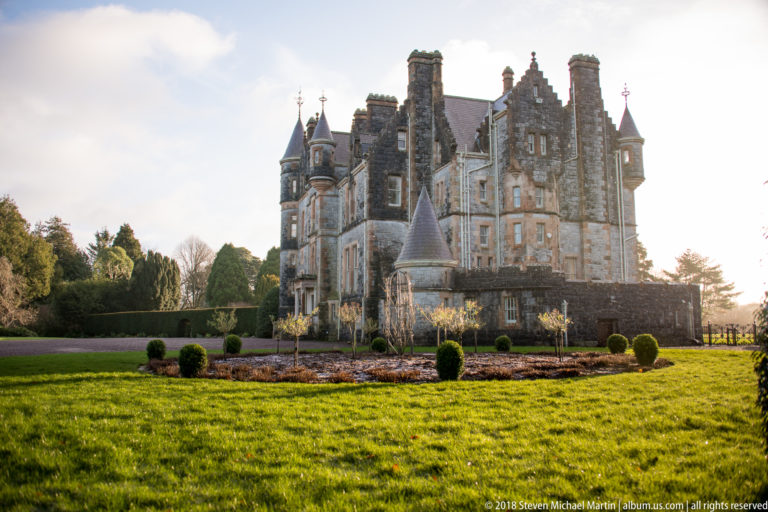 Blarney House across a green lawn, with stone walls, steep gables, turrets, and tall chimneys.