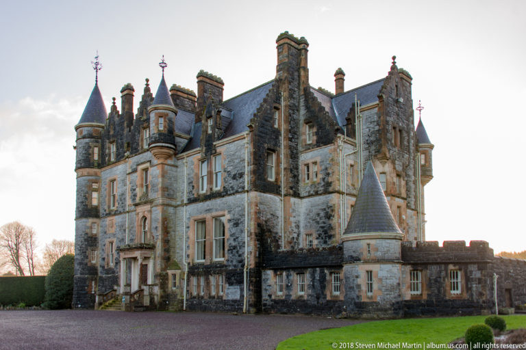 Blarney House viewed from a gravel drive, with gables, turrets, chimneys, bay projections, and many windows.