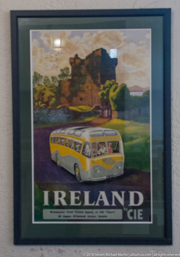 Framed Ireland travel poster showing a yellow coach below a painted castle landscape and large IRELAND lettering.