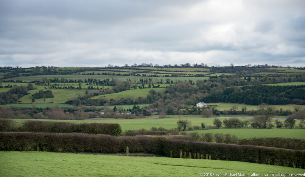 Rolling green Boyne Valley fields divided by hedgerows and trees beneath a cloudy sky.