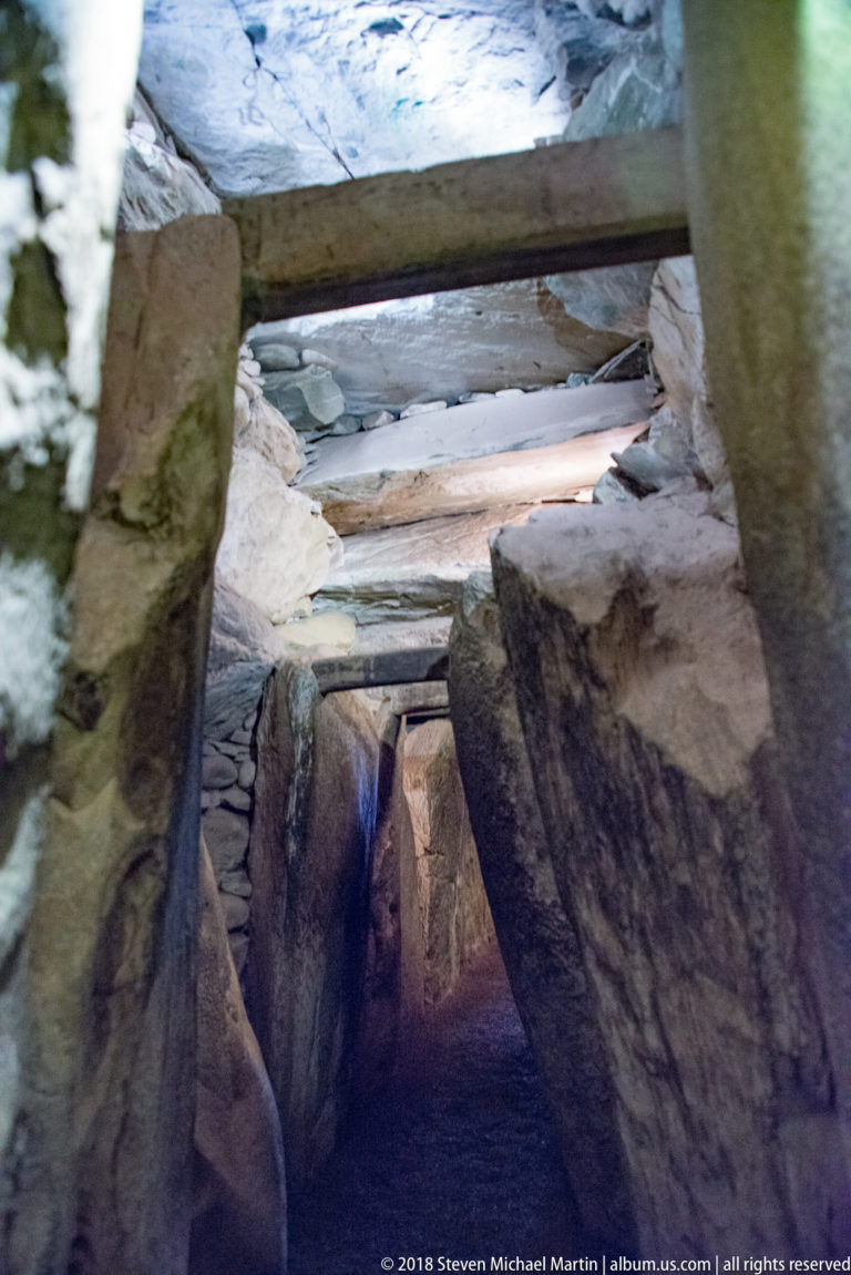 Narrow Newgrange passage lined by upright megaliths and roofed with successive horizontal stone lintels.