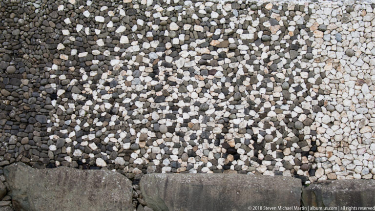 Close detail of white quartz and dark cobbles above large base stones on Newgrange’s exterior.