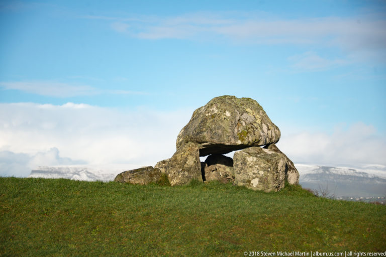 Low frontal view of a rounded capstone resting on large uprights, creating a dark chamber opening.