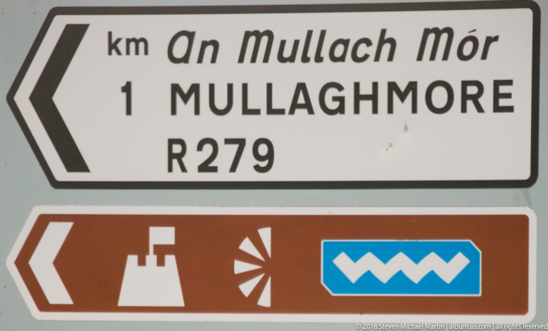 Bilingual road sign pointing left to Mullaghmore on the R279, above a brown tourist-direction panel with pictograms.