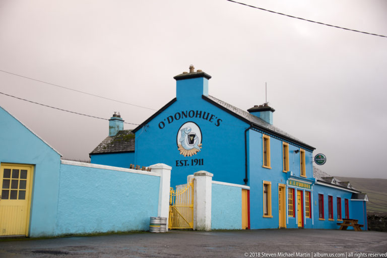 Bright blue O'Donohue's pub with yellow trim, painted façade lettering, chimneys, and “EST. 1911” beneath the name.