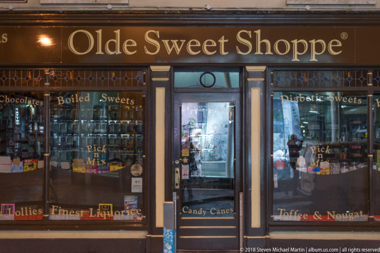 Traditional Sweet Shoppe storefront with dark wood framing, gold lettering, jars, and sweets displayed behind glass.