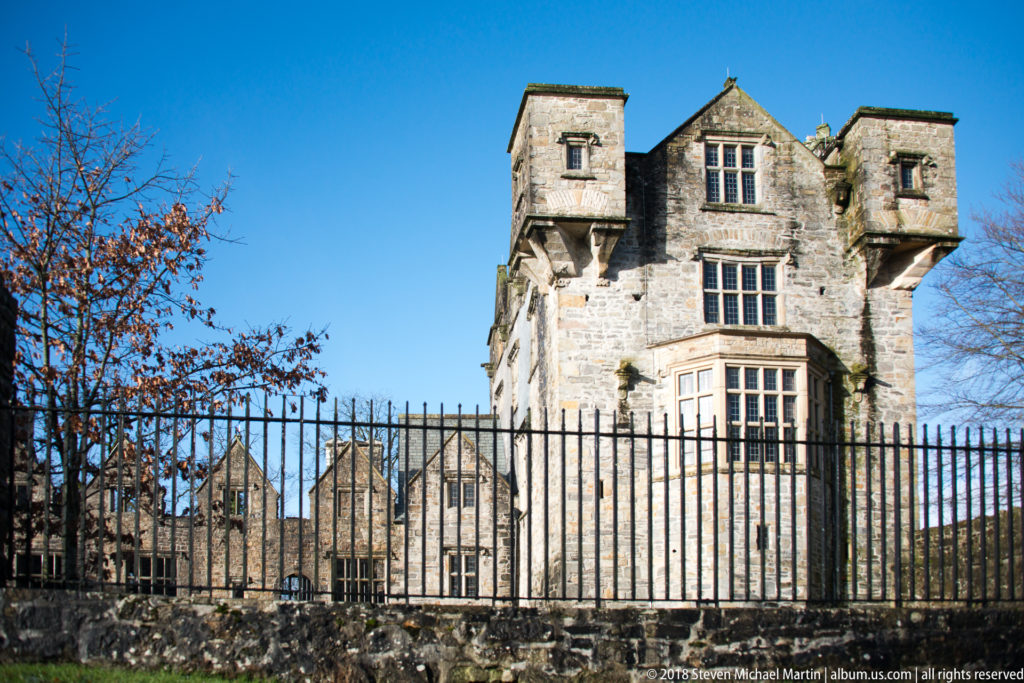 Frontal low-angle view of Donegal Castle tower with twin projecting upper chambers and mullioned windows.