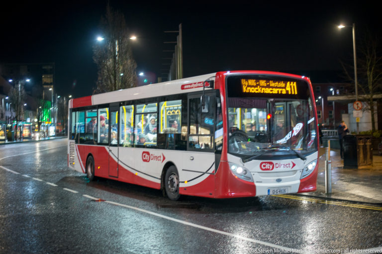 Red-and-white City Direct bus at night displaying route 411 to Knocknacarra on a wet Galway street.