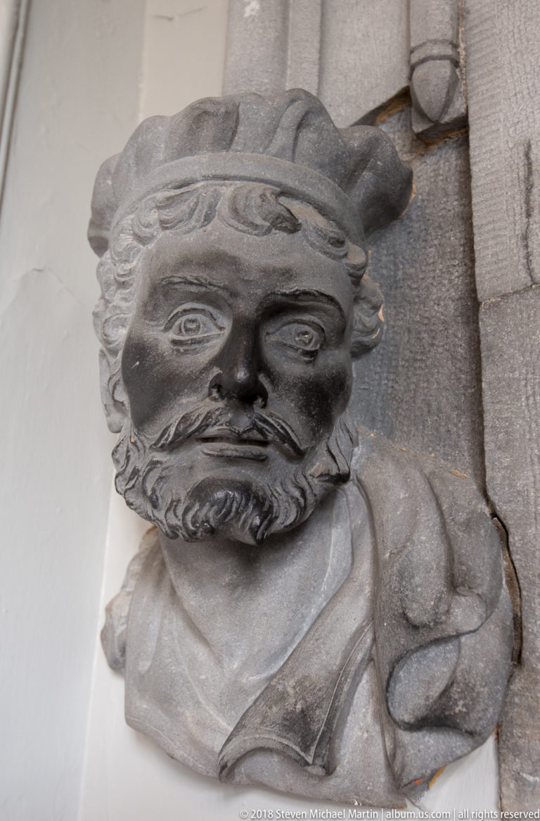 Close view of a carved bearded stone head projecting from the castle masonry.