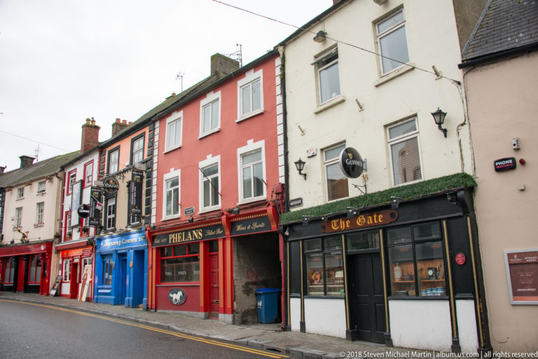 Colorful Kilkenny pub fronts, including Phelan’s and The Gate, beneath rows of upper-story windows.