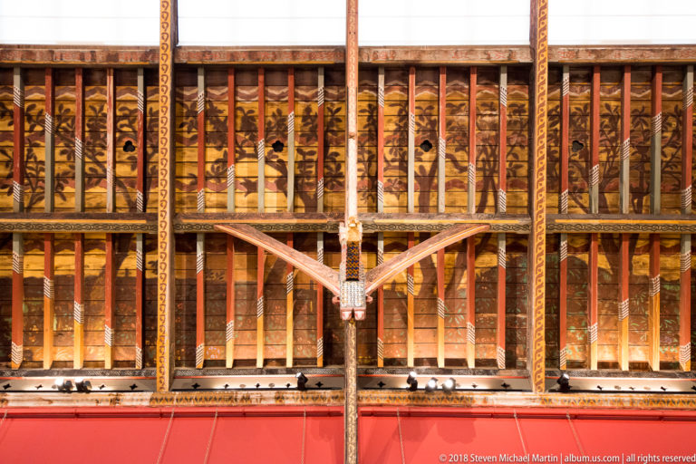Close view of richly painted timber roof trusses and braces with geometric and foliate decoration above the Picture Gallery.