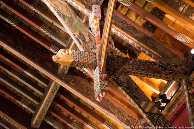Upward close view of a gilded carved animal head projecting from richly painted timber beams in the Picture Gallery roof.