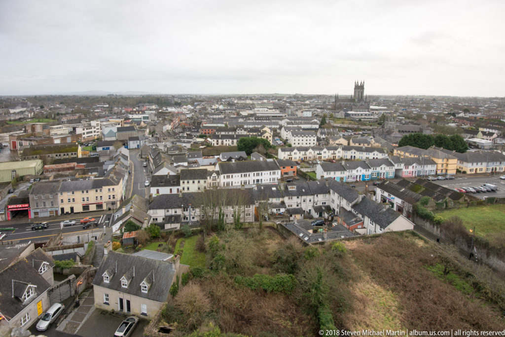 Elevated panorama over Kilkenny rooftops and streets, with church towers rising above the low-rise city.