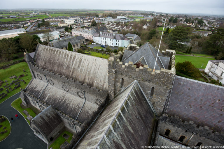 High-angle view down over St Canice’s Cathedral roof, stone walls, graveyard and surrounding Kilkenny buildings.