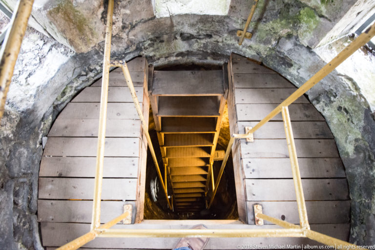 Steep wooden stairs and handrails descend through the rough stone interior of St Canice’s round tower.