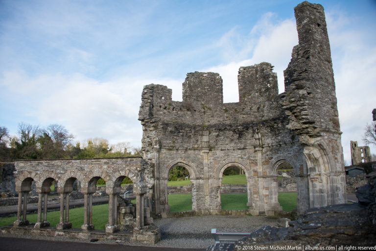 Ruined lavabo with two large lower arches beside a row of small round arches and slender columns.