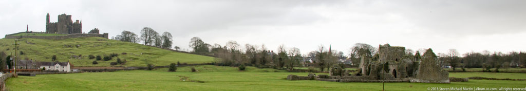 Hore Abbey ruins in green pasture with the Rock of Cashel rising on the hill in the background.