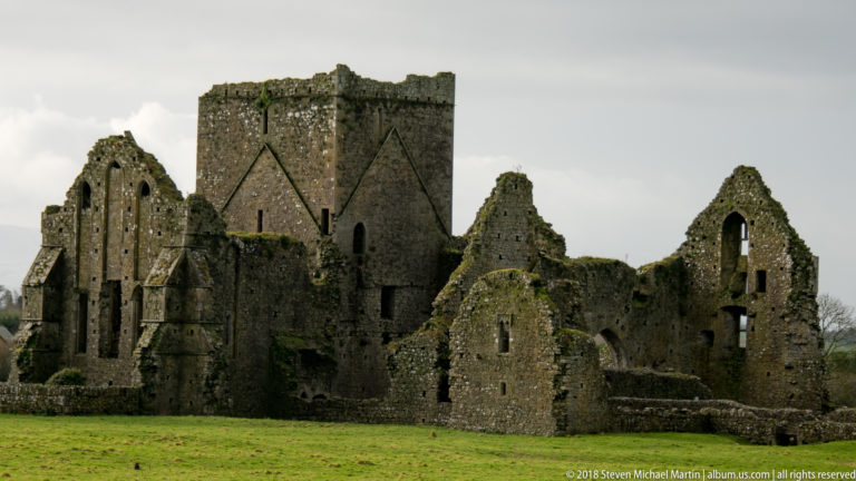 Close exterior view of roofless abbey ruins with pointed openings, broken gables, and a large square tower.