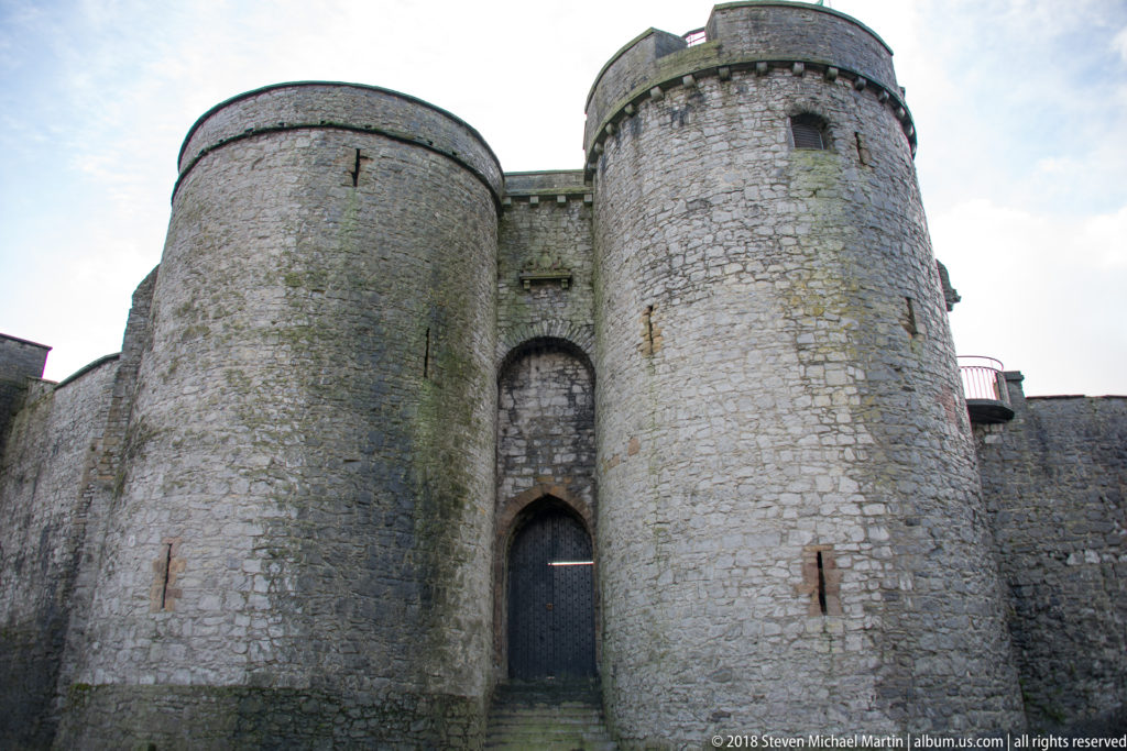 Twin round stone towers flanking a narrow arched gateway in the exterior defenses of King John’s Castle.