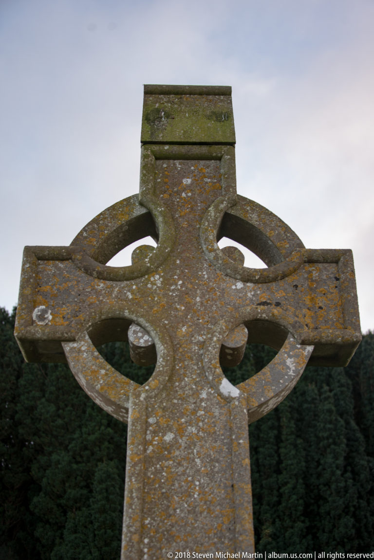 Close view of a weathered ringed Celtic cross with four open spaces and patches of lichen.