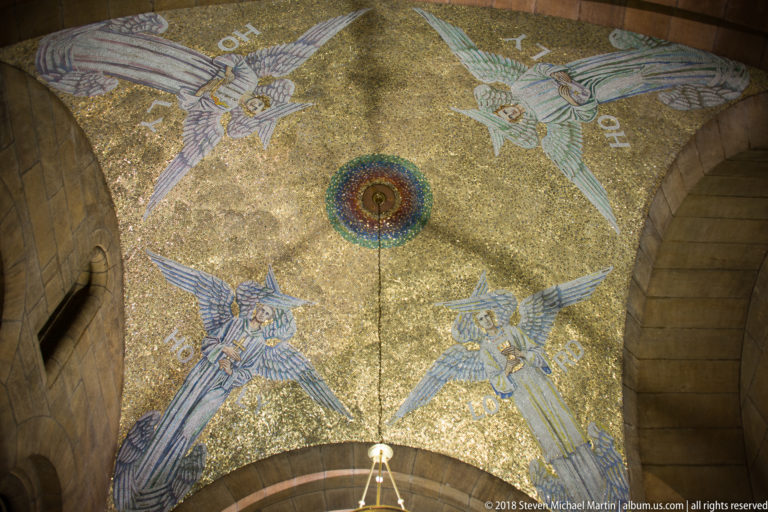 Gold mosaic ceiling vault with four winged angelic figures arranged around a central circular medallion.